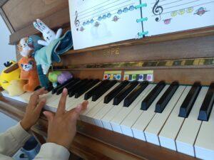 gros plan sur les mains d'une enfant donnant un concert de piano à des peluches posées sur le clavier